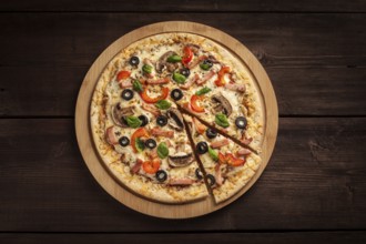 Ham pizza with (capsicum), mushrooms, olives and basil leaves on wooden board on old table