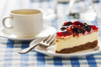 Dessert background, fruit cheese cake on plate with fork and coffee cup on blue checkered