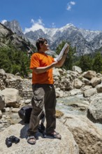 Hiker trekker studying map route on trek in Himalayas mountains. Himachal Pradesh, India, Asia