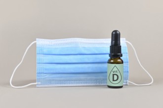 Medical face mask and bottle with vitamine drops on gray background