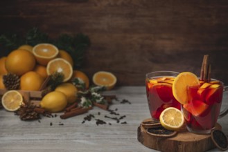 Wooden basket with oranges and lemons, two glass cups with punch, cloves and cinnamon sticks,