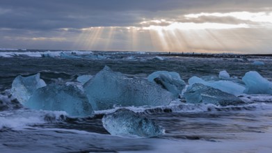 Waves breaking on icebergs on the black beach of Breidamerkursandur, near Jökullsarlon, Sudurland,