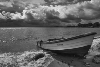 Rowing boat on sandy beach in front of dramatic storm clouds, black and white, Rügen,