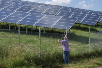 Man photographing a fenced photovoltaic plant, Pfronten, Allgäu, Bavaria, Germany, Europe