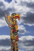 Colourful wooden carved Canadian totem pole against cloudy sky