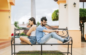 Upset couple sitting back to back on a park bench. Concept of a couple arguing in a park. Upset