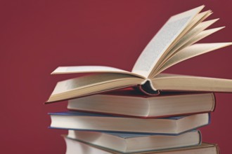 Stack of old hardcover books on dark red background