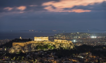 View over the sea of houses of Athens, illuminated Parthenon temple on the Acropolis, dramatic