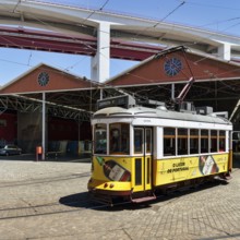 Historic yellow tram, Eléctrico, line 28 in front of tram depot and repair shop, Lisbon, Portugal,