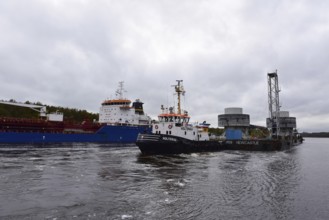 Tugboat towing a pontoon with offshore installation in the Kiel Canal, Schleswig-Holstein, Germany,