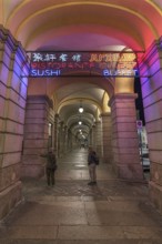 Nocturnal illuminated advertising in the historic arcade at the harbour, Genoa, Italy, Europe