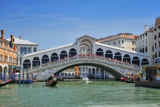 VENICE, ITALY, JULY 19, 2019: Rialto bridge with boats and gondolas passing under on Grand Canal,