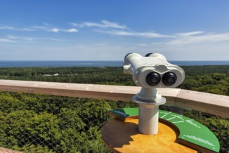 White telescope on viewing platform points towards the Baltic Sea, treetop path at the Rügen