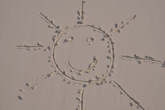 Sun face drawn in the sand