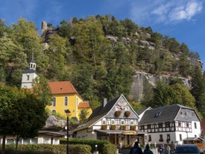 Half-timbered houses and small village church on a slope, half-timbered houses in front of rocks,