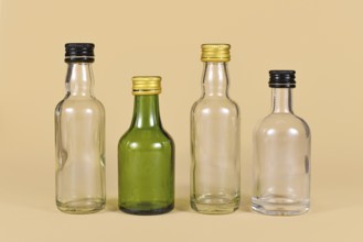 Different empty green and white glass bottles on beige background