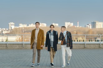 Three young men in autumn clothes are walking down the street