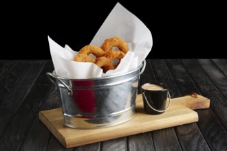 Snack for beer. Fried onion rings with sauce served in metal backet