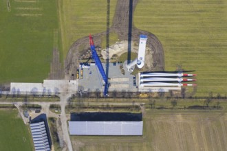 Aerial view over construction site showing rotor blades on the ground and building crane assembling