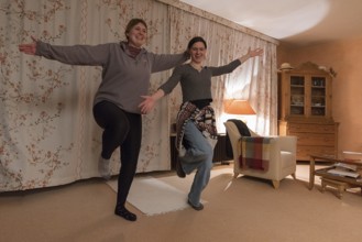 Two young woman dancing in the living room, Franconia, Bavaria, Germany, Europe