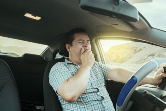 View of a sleepy driver in his car. Tired driver yawning in the car, concept of man yawning while