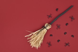 Halloween witch broom and spiders on dark red background with copy space