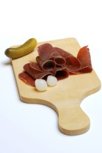 Bündner dried meat on wooden board, with delicacy gherkin and silver onions, beef, Bündner dried