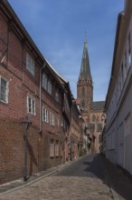 Old town alley with historic houses, Nikolai Church in the back, Lüneburg, Lower Saxony, Germany,