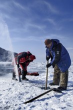 Digging a hole in the ice for scuba diving, Lake Baikal, Olkhon Island, Pribaikalsky National Park,