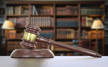 Gavel resting on a table inside a law office with bookshelf of law books in the background