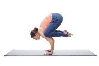 Beautiful sporty fit yogini woman practices yoga asana Bakasana, crane pose arm balance isolated on