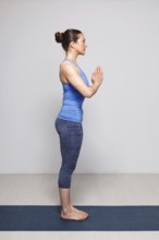 Woman doing Hatha Yoga asana Tadasana namaste -Mountain pose with salutation on yoga mat in studio