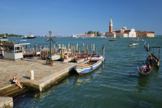 VENICE, ITALY, JULY 19, 2019: Gondolier with client tourists in gondola in lagoon of Venice by