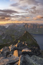 View over mountain peaks and sea, dramatic sunset, mountaineers at Hermannsdalstinden, with fjord