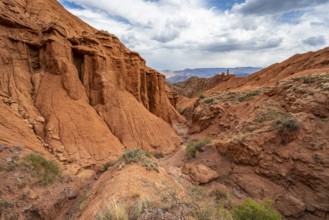 Eroded mountain landscape with sandstone cliffs, canyon with red and orange rock formations,