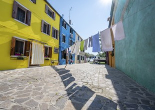 Clothesline between colourful houses, colourful house facades, alleys on the island of Burano,