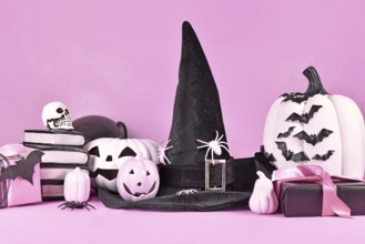 Pink Halloween decor with black and white pumpkins, witch hat, spell books, gifts and spiders