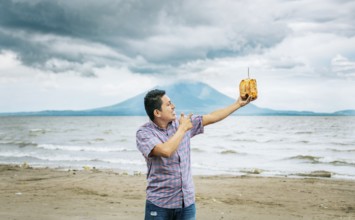 Young man vacationing and enjoying a coconut on the beach. Smiling man holding and pointing at a