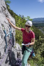 Climber on the rope looking at the topo, multi-pitch climbing, Via la Bellezza della Venere, Garda