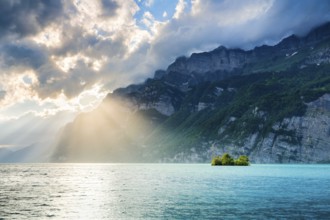 Evening sun rays on Lake Walen with chive island in the turquoise water and mountain range Schären