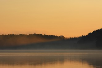 Foggy mood with a ray of light from the rising sun over a lake in Mecklenburg, Müritz National