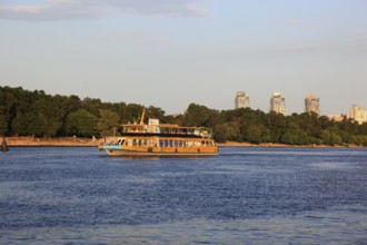 Excursion boat on the river Dnepr and skyscrapers in the background, Kiev, Ukraine, Europe