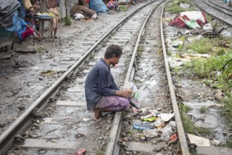 A man searches for meal times between the railway tracks, Tejgaon Slum Area, Dhaka, Bangladesh,