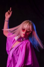 Sideview shot of a stylish girl with red lips and blond hair wearing pink dress and earphones.