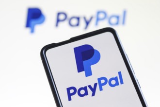 PayPal logo of the online payment provider on a mobile phone and screen