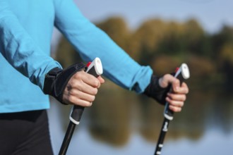 Nordic walking exercise adventure hiking concept, closeup of woman's hand holding nordic walking