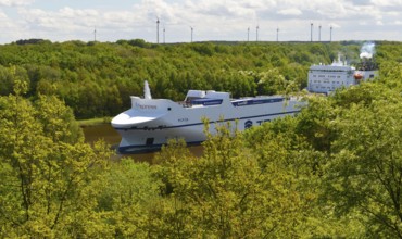 Car transporter, container ship in the forest on the Kiel Canal, Schleswig-Holstein, Germany,