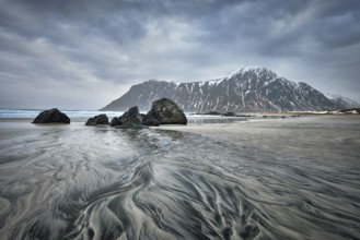 Rocky coast of fjord of Norwegian sea in winter with snow. Skagsanden beach, Lofoten islands,