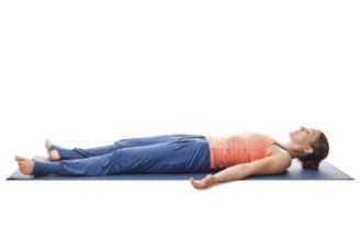 Beautiful sporty fit yogini woman relaxes in yoga asana Savasana, corpse pose isolated on white