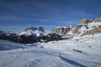 View of a ski resort piste with people skiing in Dolomites in Italy. Ski area Belvedere. Canazei,